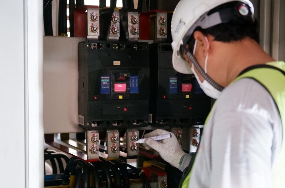 Técnico inspecionando disjuntores em painel elétrico